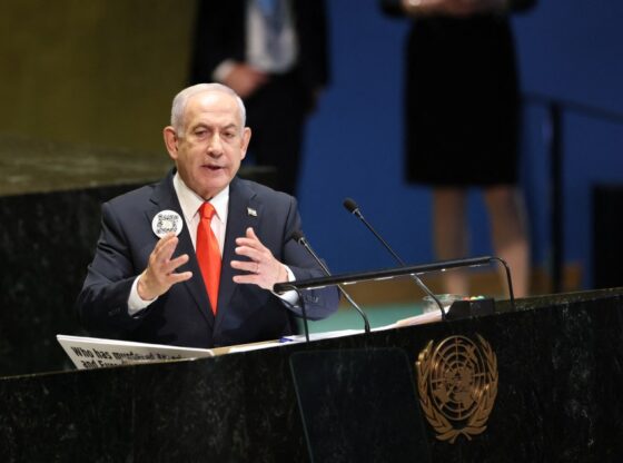 Israeli Prime Minister Benjamin Netanyahu speaks at the United Nations General Assembly, wearing a button with a QR code.