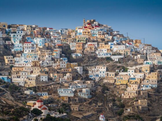 View of the ancient village Olympos, Karpathos island, Greece, built into a hillside with colorful homes.