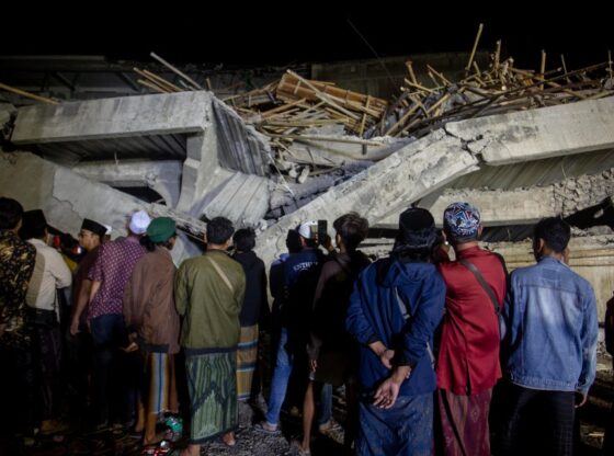 Relatives standing in front of a collapsed building during a rescue operation at an Islamic boarding school.