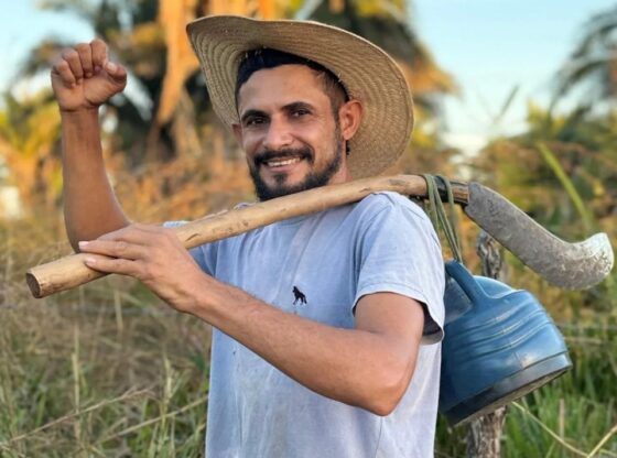 REINALDO DA SILVA MELO, ALSO KNOW "King of Juquira" influencer, carrying a scythe over his shoulder.