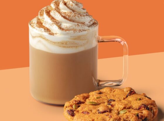 A Starbucks Pumpkin Spice Latte with whipped cream and a cookie with cranberries and pumpkin seeds.