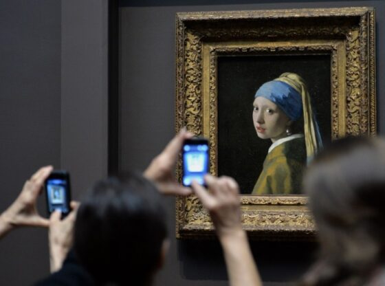 People view "Girl with a Pearl Earring (c. 1665)" by Johannes Vermeer in the exhibition "Vermeer, Rembrandt, and Hals: Masterpieces of Dutch Painting from the Mauritshuis" October 21, 2013 at the Frick Collection in New York. The special exhibition is the final US venue of a global tour of paintings from the Royal Picture Gallery Mauritshuis in The Hague, the Netherlands and runs from October 22, 2013 to January 19, 2014. AFP PHOTO/Stan HONDA (Photo by STAN HONDA / AFP) (Photo by STAN HONDA/AFP via Getty Images)