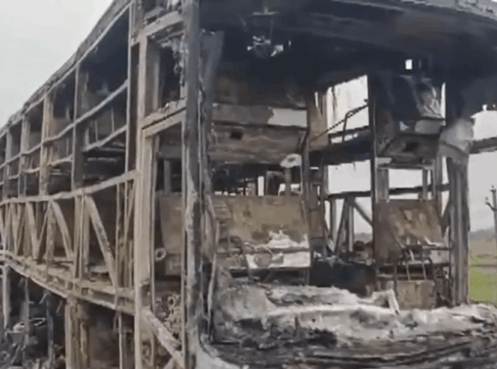 Remains of a burned-out bus, charred to its skeletal frame, are seen from the side and front.