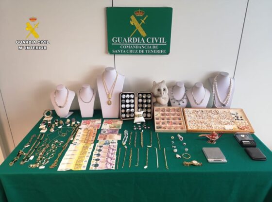 Stolen jewelry and cash recovered by police, laid out on a green cloth.