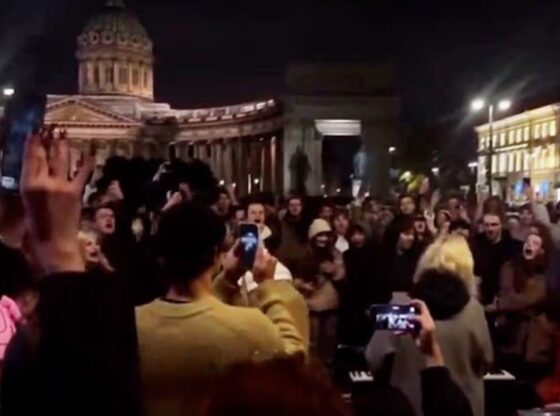 An image collage containing 1 images, Image 1 shows A crowd of people filming a concert at night in front of the Kazan Cathedral