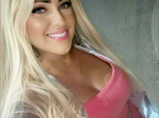 A smiling woman with long blonde hair and a pink top.
