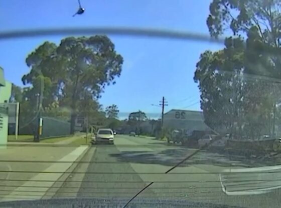 A helicopter in the sky with a street view from inside a car.