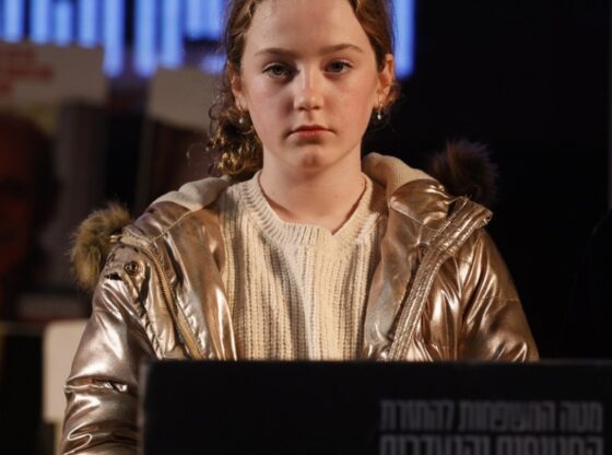 Former hostage Emily Hand standing in front of a podium during a rally in Hostage Square in Tel Aviv.