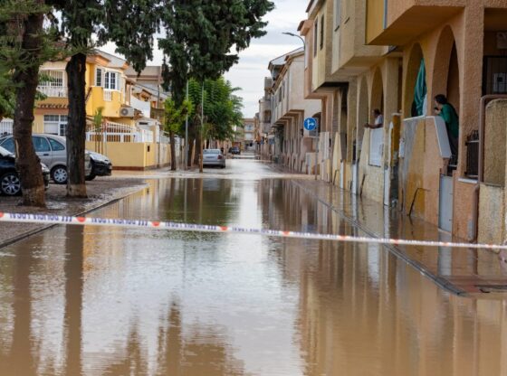 A flooded street in Los Alcazares, Spain, with a "LOCAL POLICE" barrier tape stretched across it.