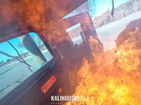 A vehicle on fire, viewed from inside, with flames obscuring part of the windshield.