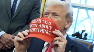 US President Donald Trump holds a cap that reads 'Trump was right about everything'.