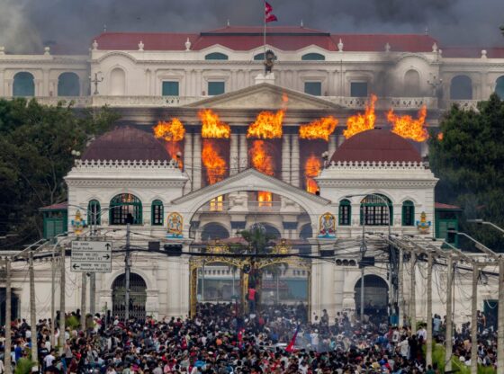 Fire and smoke rise from the Singha Durbar palace, which houses government and parliament buildings, as protesters gather below during violent demonstrations in Kathmandu.