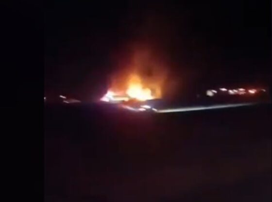 Nighttime image of a large fire on the ground, illuminating the dark surroundings.