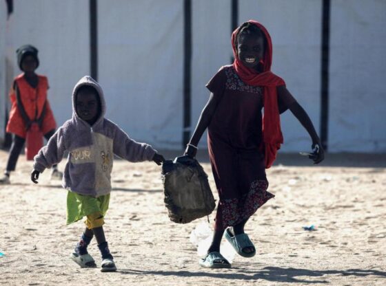 Two children refugees after the Al Fasher massacre carrying a can of water.