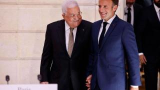 A file photo from 2022 shows French President Emmanuel Macron and Palestinian President Mahmoud Abbas smiling as they arrive for a joint press conference in Paris.