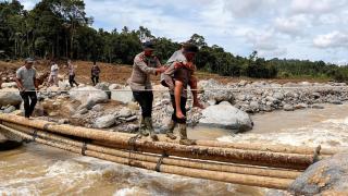 Police officers rescue a man on the island of Sumatra, affected by severe flooding.