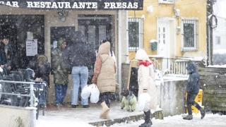 Several people enter a restaurant during the snowfall in Lugo