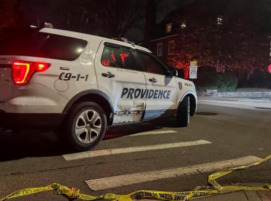 A police car passes police tape in the street following a shooting at Brown University in Providence.