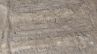 Aerial view taken with a drone of the footprints left by an excavator in the ground covering the mass grave in the Dhumair desert.